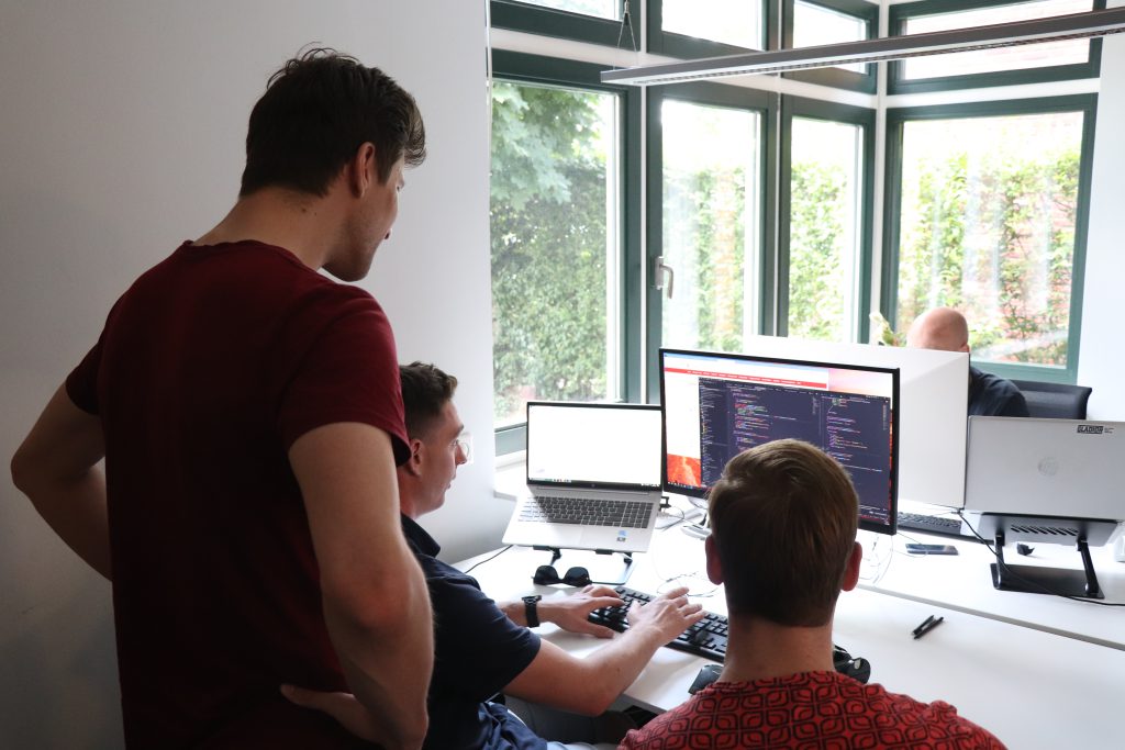 Drie collega ontwikkelaars die samen aan een applicatie werken.